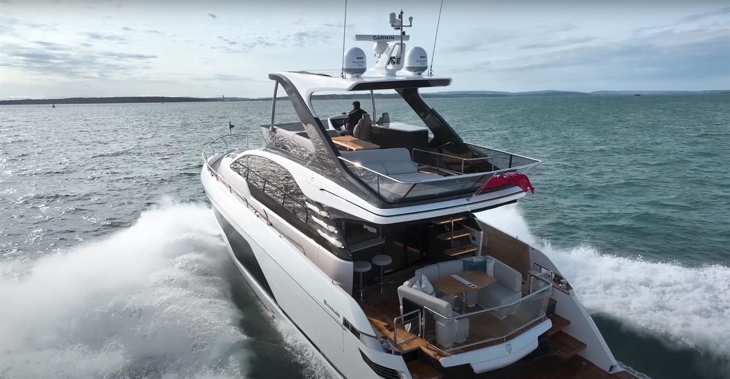 Luxury yacht cruising on water with a captain at the helm, featuring outdoor seating and a sleek modern design.